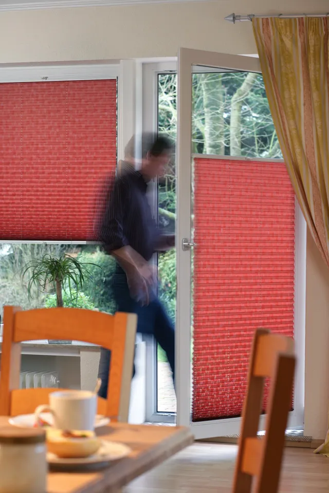 Rote Plissées als Sichtschutz an Fenstern und einer verglasten Tür